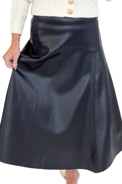 Front close view of woman wearing cream sweater with black faux leather skirt against white studio background.