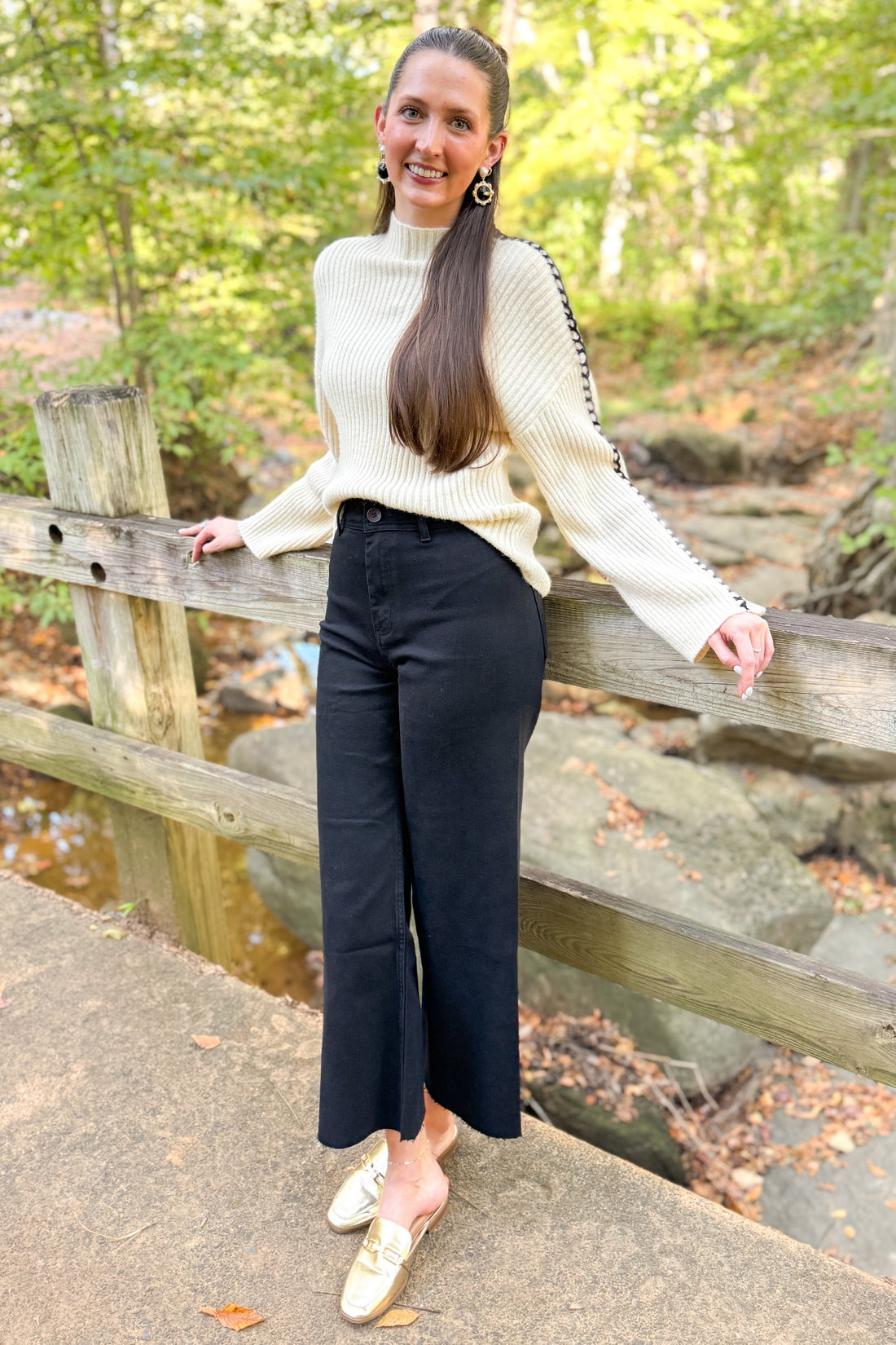 Outdoor picture of woman wearing Oatmeal Ribbed Stitch Detail Sweater and black jeans with trees in the background.