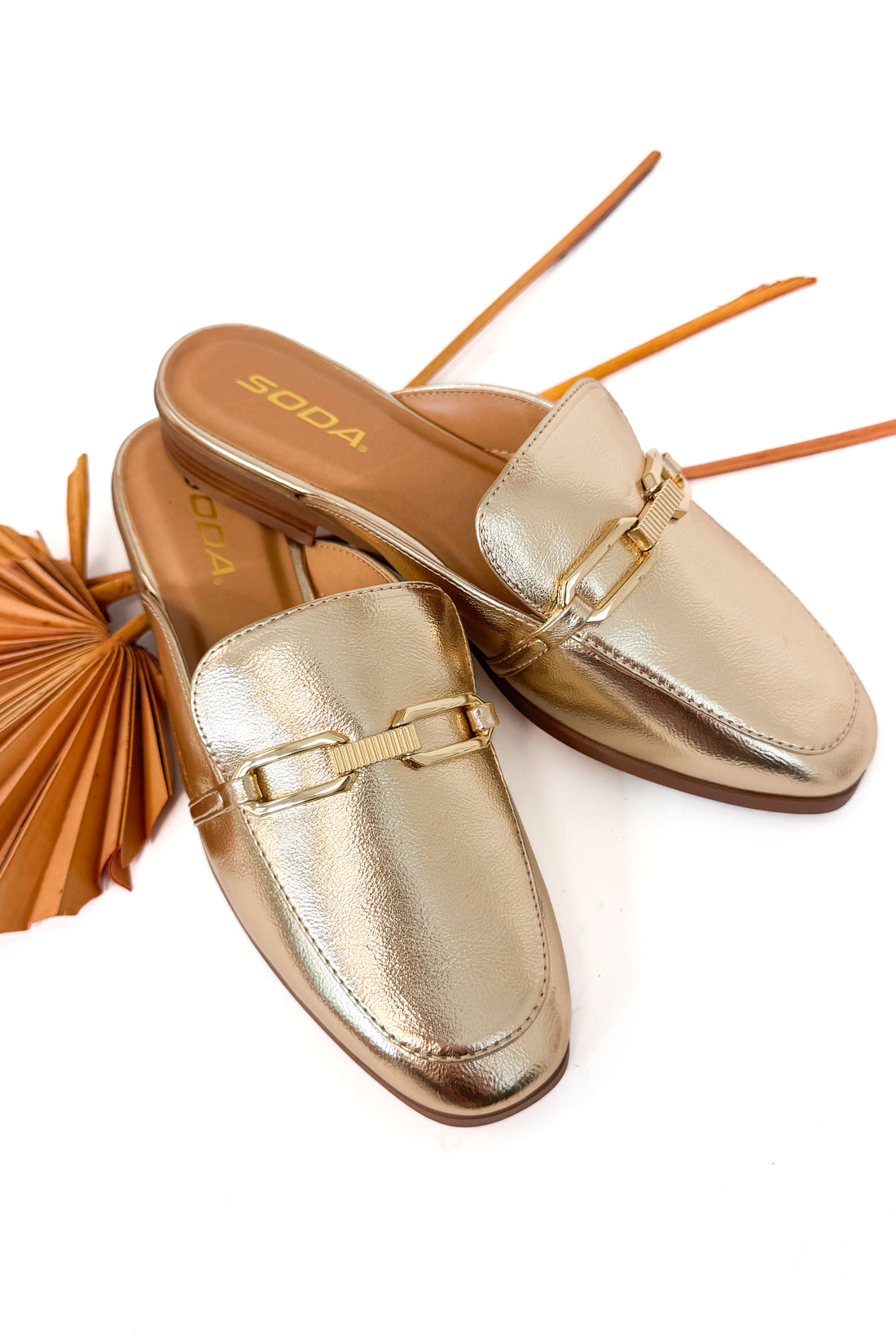 Gold metallic loafers on a white background