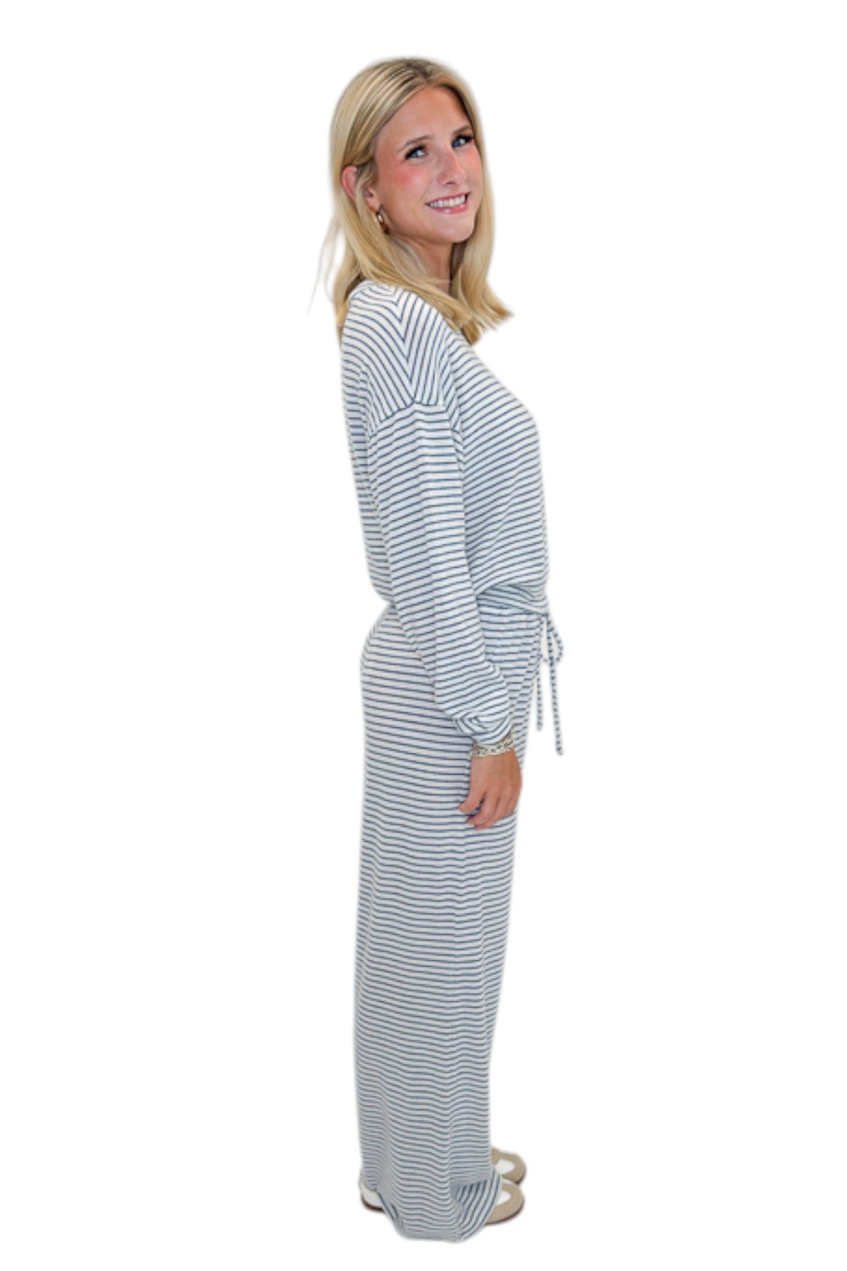 Side view of woman wearing Swagger Boutique’s Eclipse Classic Stripe Pants by Z Supply with Long Sleeve Top against white studio background.
