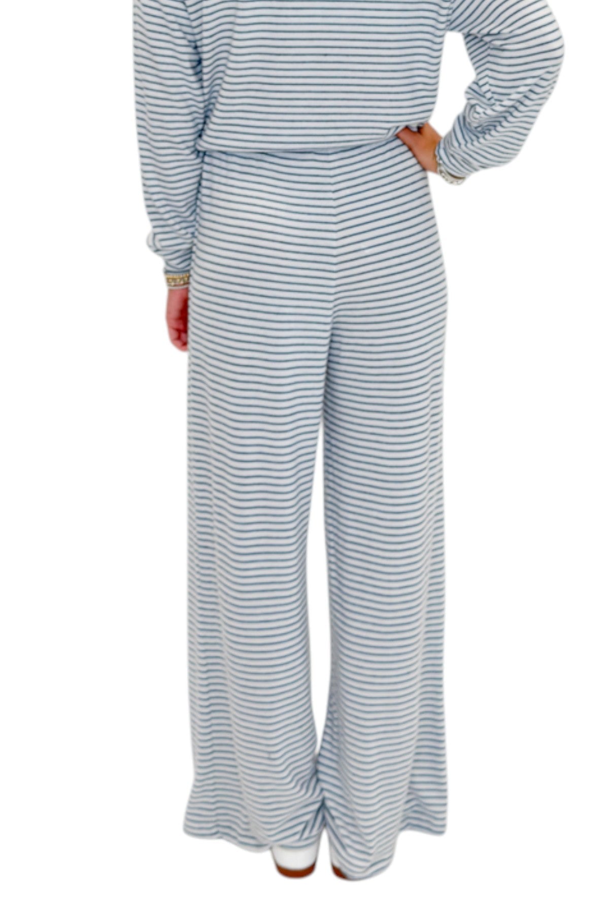 Back view of woman wearing Swagger Boutique’s Eclipse Classic Stripe Pants by Z Supply with Long Sleeve Top against white studio background.