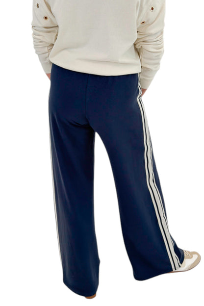 Back view of woman wearing Swagger Boutique’s Sandstone Axel Grommet Sweatshirt by Z Supply with Eclipse Breakaway Track Pants by Z Supply against white studio background.