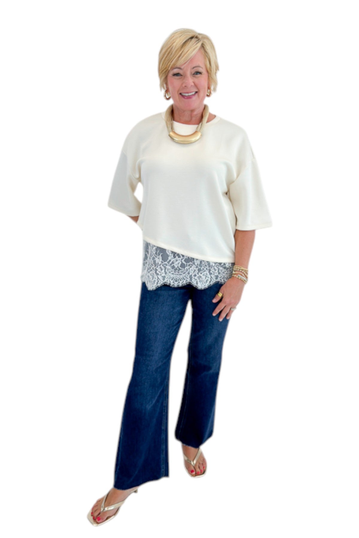 Front view of woman wearing Swagger Boutique’s Ecru Asymmetrical Lace Hem Top by Entro with jeans against white studio background.
