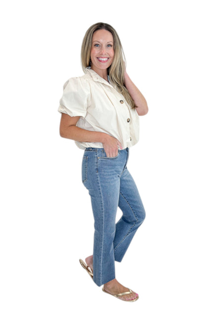 Side view of woman wearing Swagger Boutique’s Ecru Bubble Hem Button Up Top by Entro with jeans against white studio background.