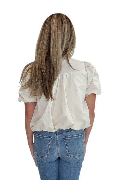 Back view of woman wearing Swagger Boutique’s Ecru Bubble Hem Button Up Top by Entro with jeans against white studio background.
