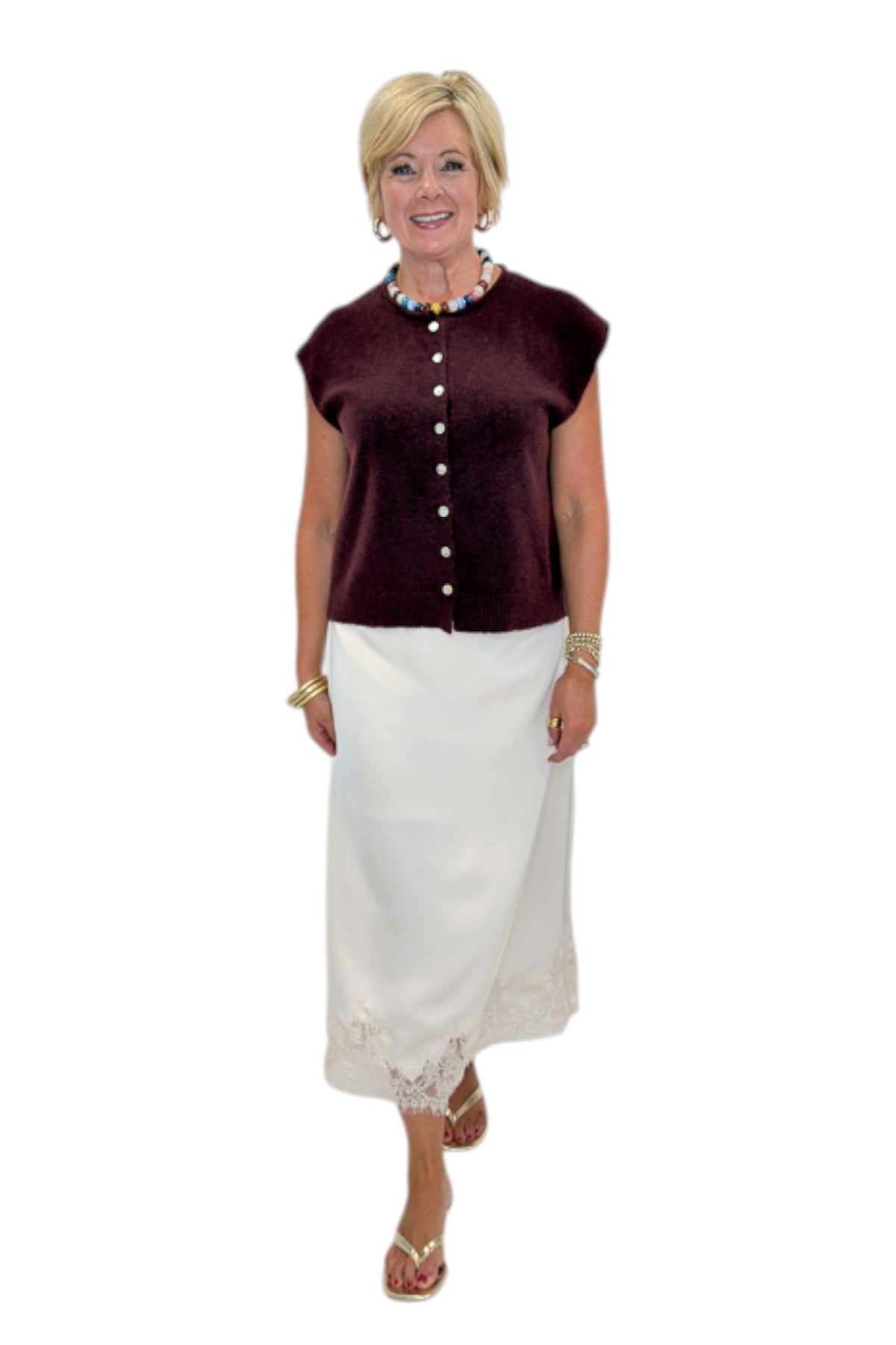 Front view of woman wearing Swagger Boutique’s Wine Sleeveless Button Up Sweater with Ecru Lace Lined Satin Skirt by Entro against white studio background.