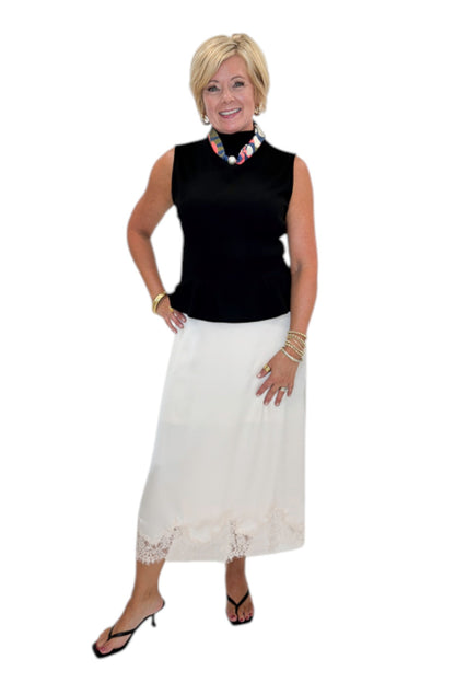 Front view of woman wearing Swagger Boutique’s black top with Ecru Lace Lined Satin Skirt by Entro against white studio background.