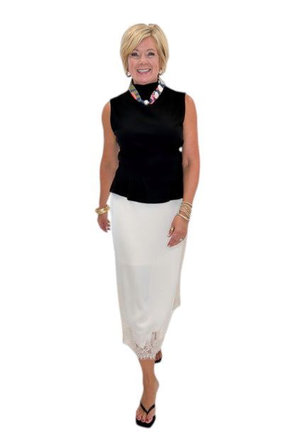 Front view of woman wearing Swagger Boutique’s black top with Ecru Lace Lined Satin Skirt by Entro against white studio background.