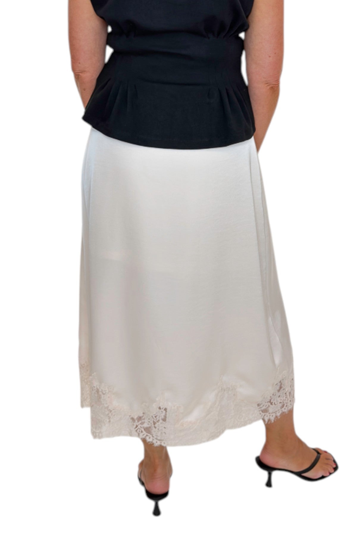 Back view of woman wearing Swagger Boutique’s black top with Ecru Lace Lined Satin Skirt by Entro against white studio background.