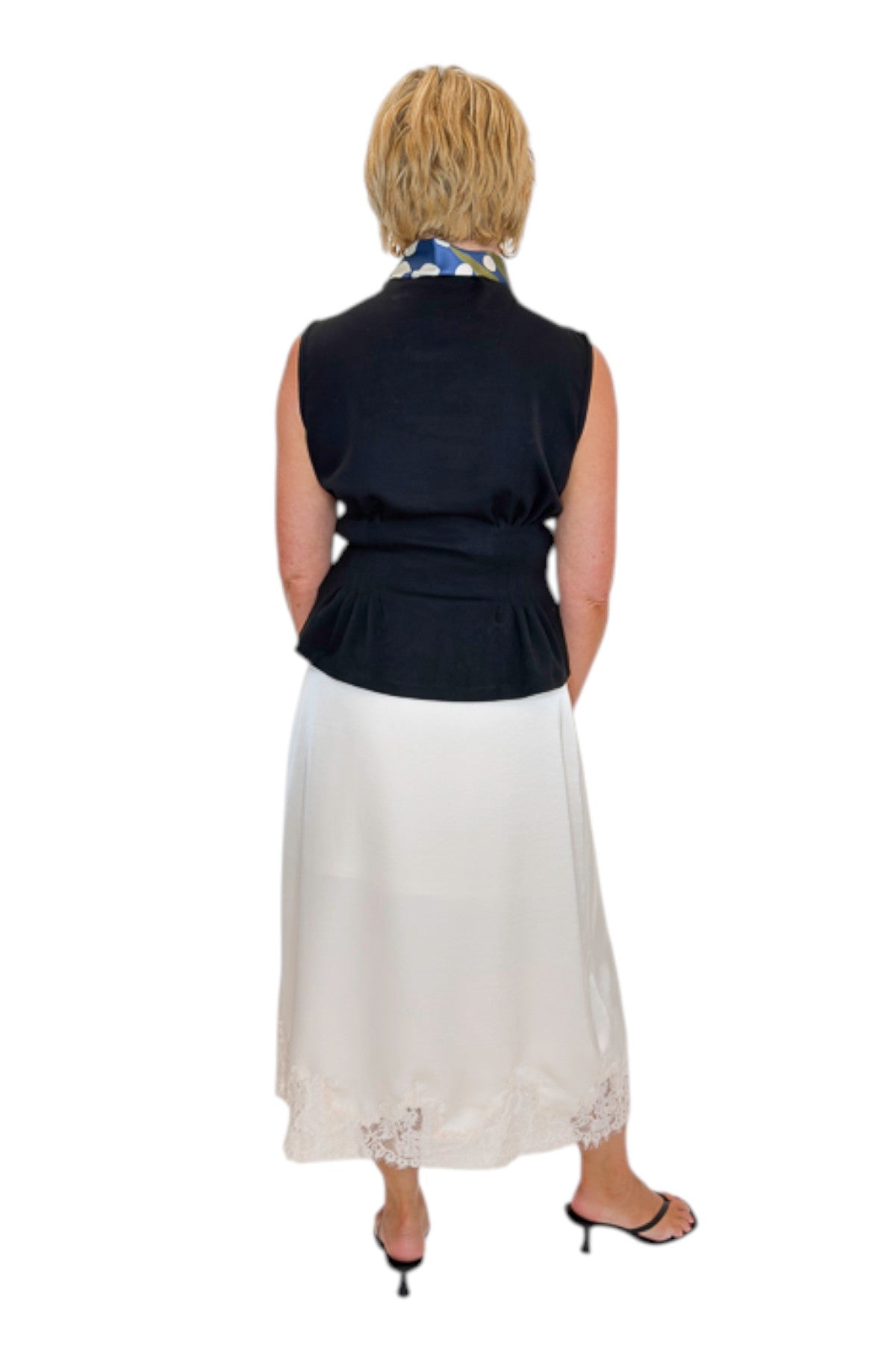 Back view of woman wearing Swagger Boutique’s black top with Ecru Lace Lined Satin Skirt by Entro against white studio background.