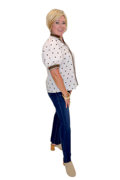 Side view of woman wearing Swagger Boutique’s Ecru &amp; Brown Polka Dot Button Up Top by Entro with jeans against white studio background.