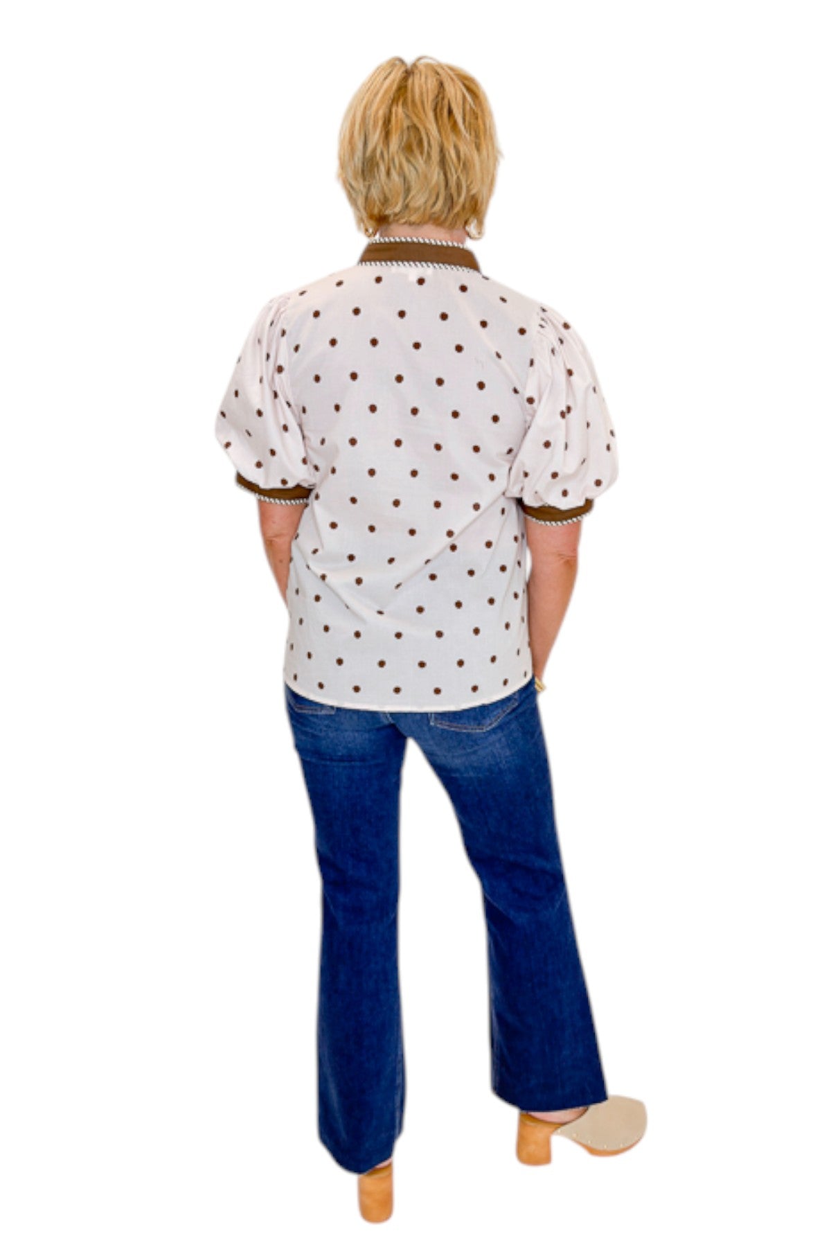 Back view of woman wearing Swagger Boutique’s Ecru &amp; Brown Polka Dot Button Up Top by Entro with jeans against white studio background.