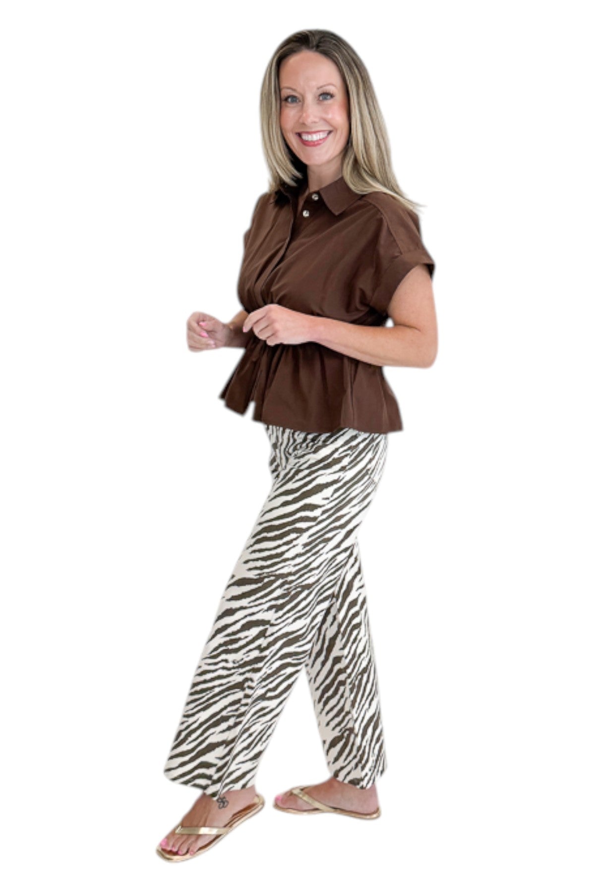 Side view of woman wearing Swagger Boutique’s Brown Cinched Waist Short Sleeve Top with zebra jeans against white studio background.