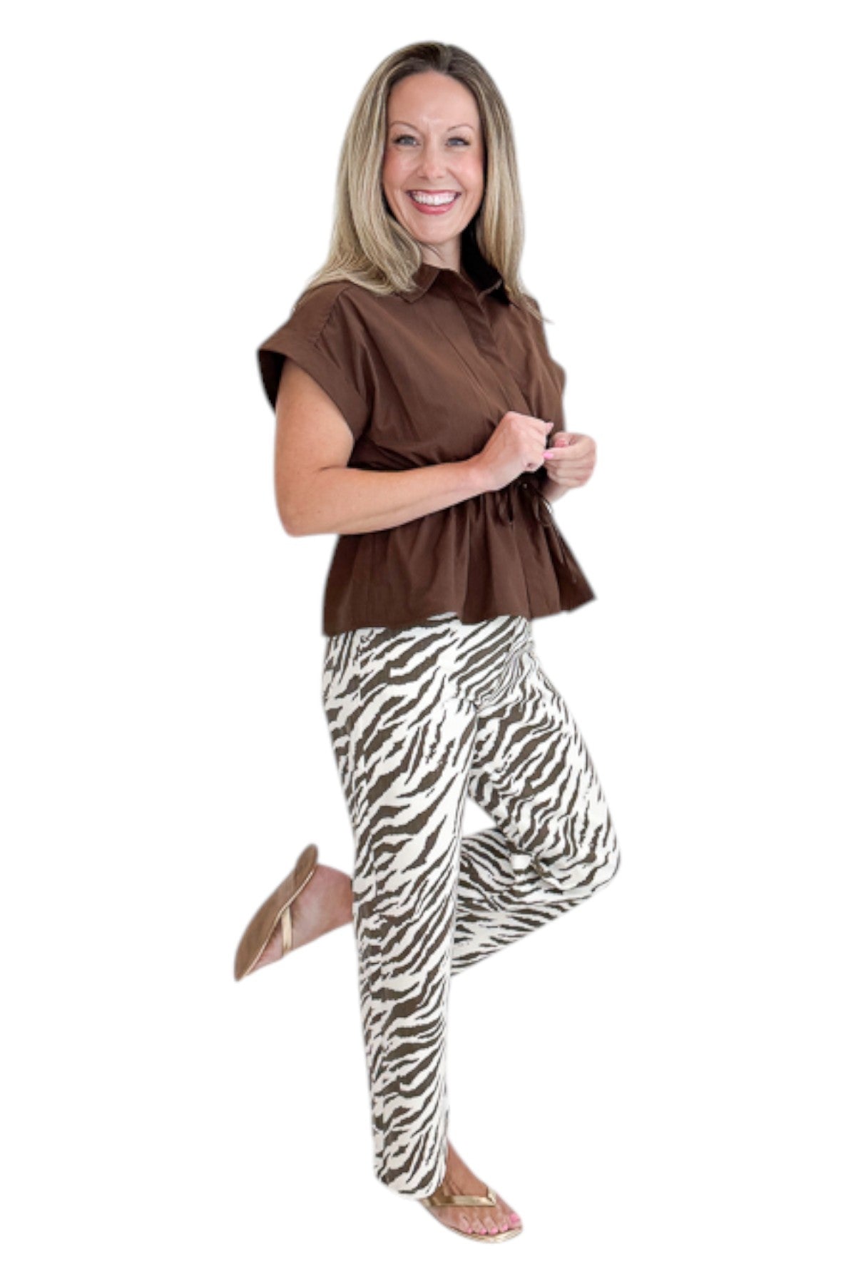 Side view of woman wearing Swagger Boutique’s Brown Cinched Waist Short Sleeve Top with zebra jeans against white studio background.