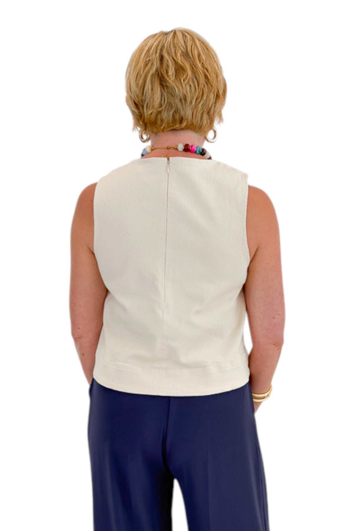 Back view of woman wearing Swagger Boutique’s Ecru Horsebit Buckle Tank by Entro with Navy High Waisted Trousers by Skies Are Blue against white studio background.