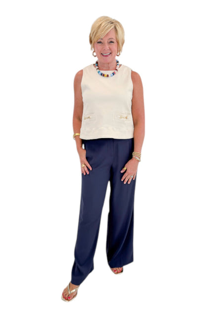 Front view of woman wearing Swagger Boutique’s Ecru Horsebit Buckle Tank by Entro with Navy High Waisted Trousers by Skies Are Blue against white studio background.