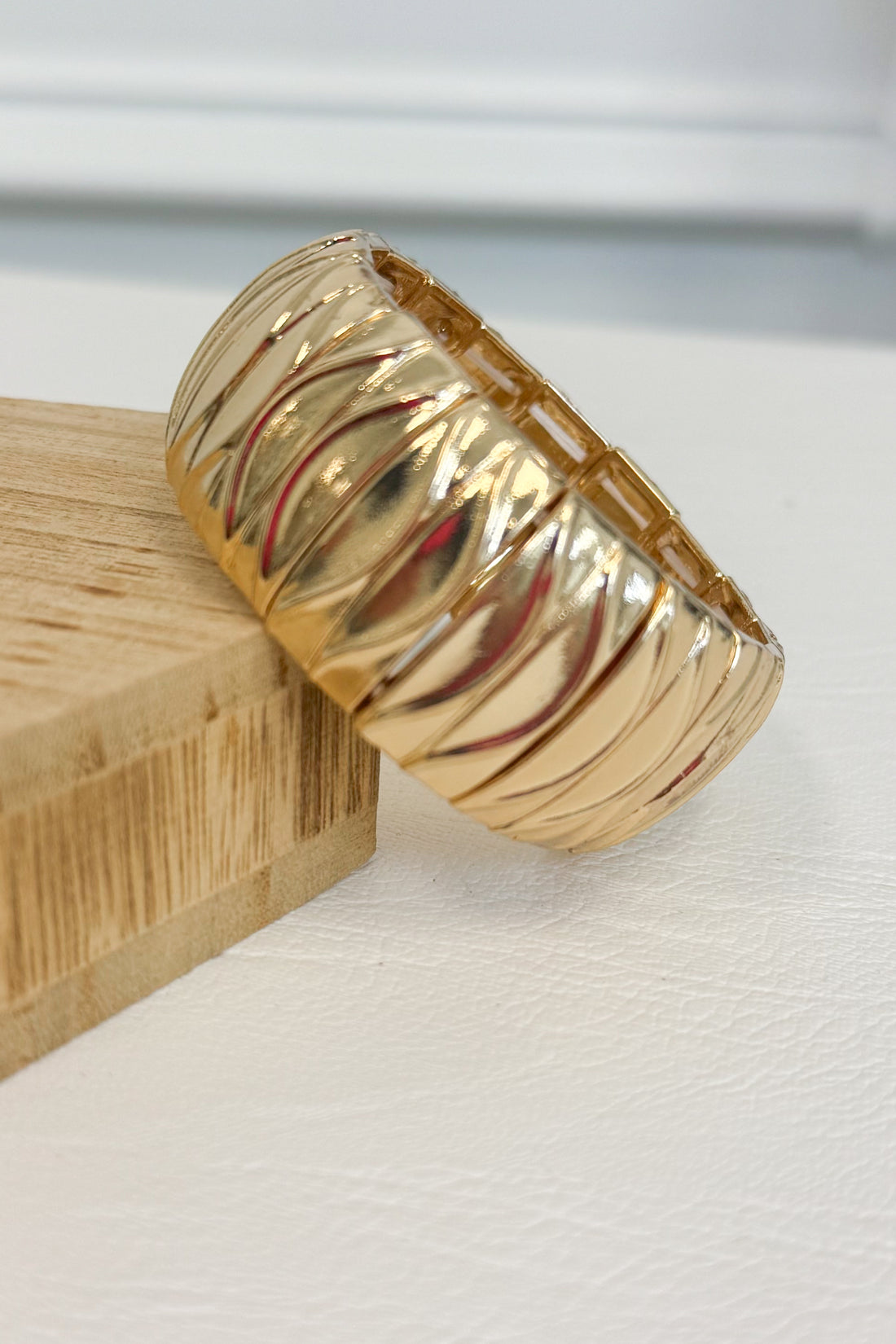 Gold-tone textured bracelet with an intricate raised pattern and rounded design on a white studio background
