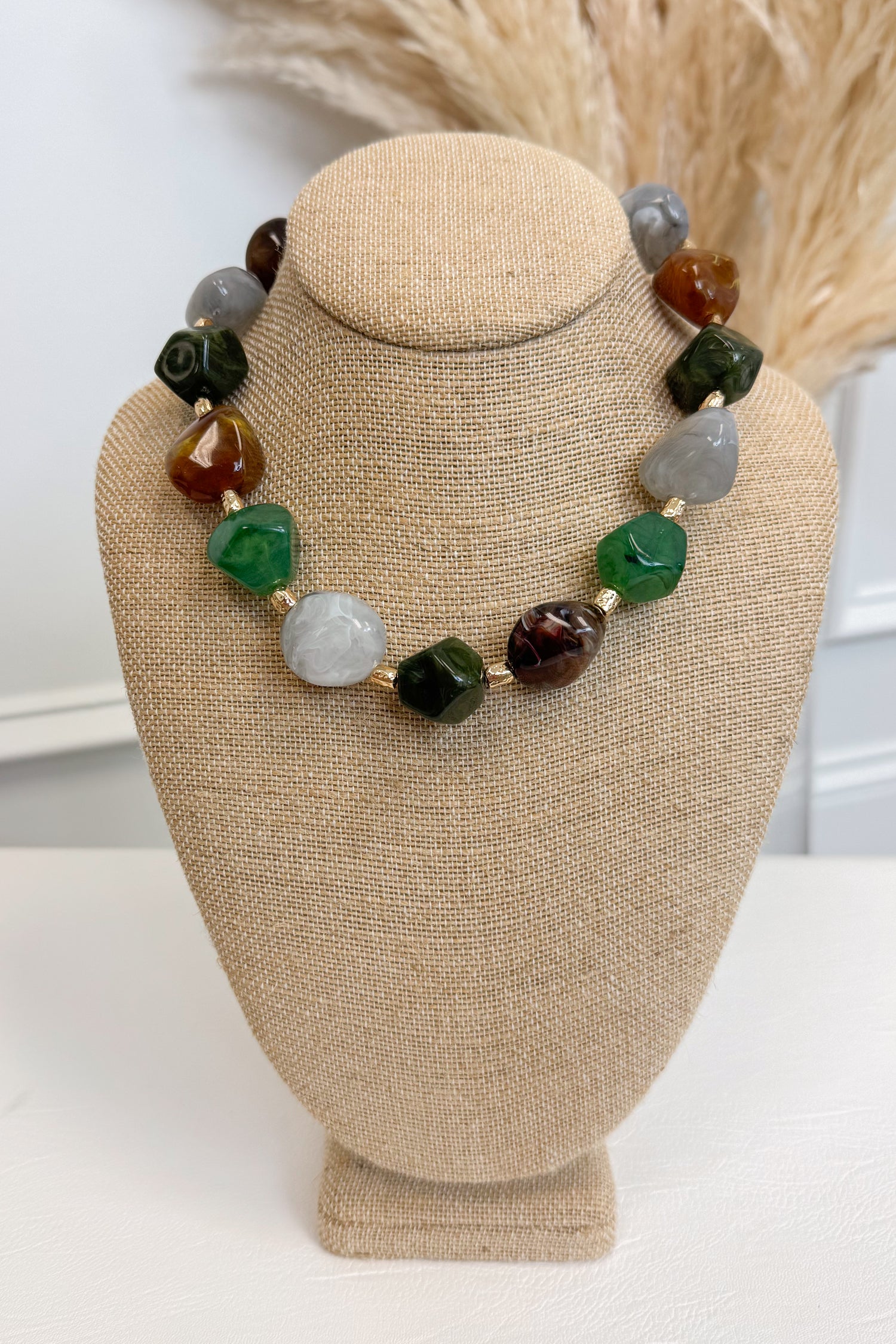 front view of multicolor nugget shaped beaded necklace with gold accents on bust 