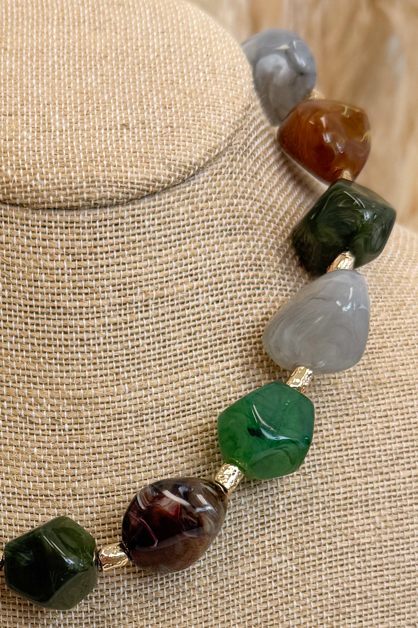 side view of multicolor nugget shaped beaded necklace with gold accents on bust 