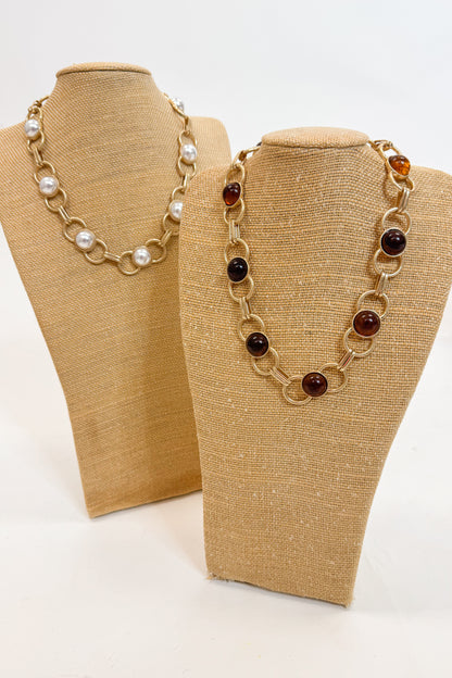 Two necklaces on mannequin busts with a plain background