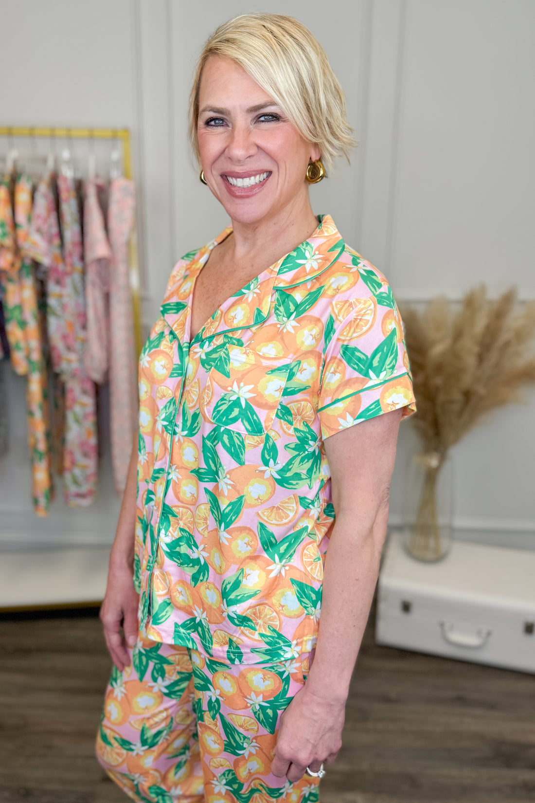 Woman wearing a floral pajama set in a room with clothing racks in the background
