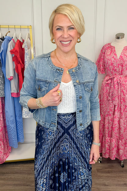 Front view of woman wearing Medium Wash Collarless Denim Jacket by Just Black Denim with top and skirt. 