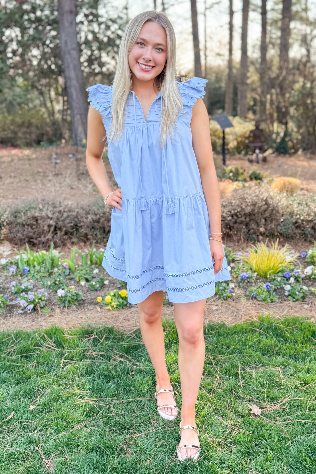 Front view of woman wearing Light Blue Eyelet Detail Dress with sandals outside at a garden.