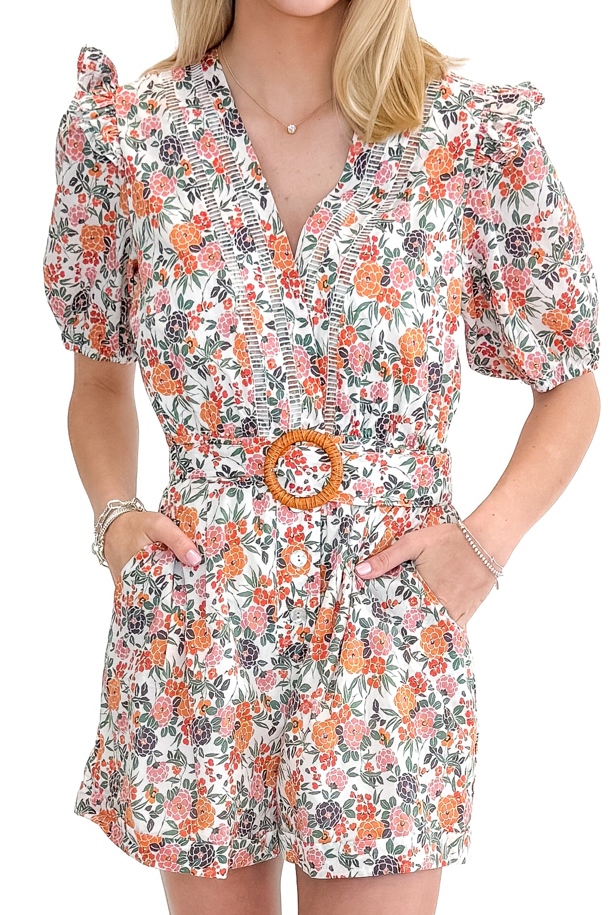 Front detail view of woman wearing Orange Floral &amp; Lace Romper With Belt against white studio background.