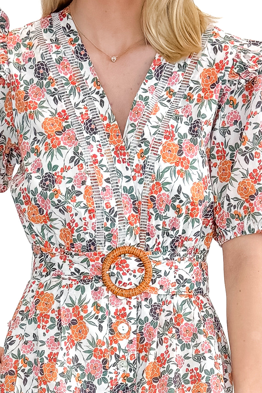 Front detail view of woman wearing Orange Floral &amp; Lace Romper With Belt against white studio background.