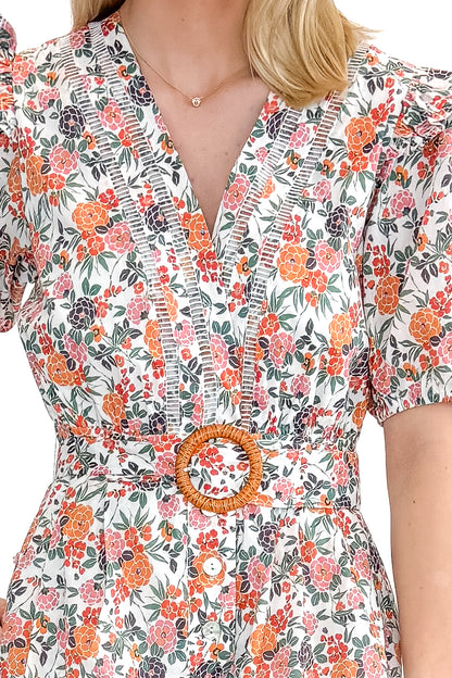 Front detail view of woman wearing Orange Floral &amp; Lace Romper With Belt against white studio background.