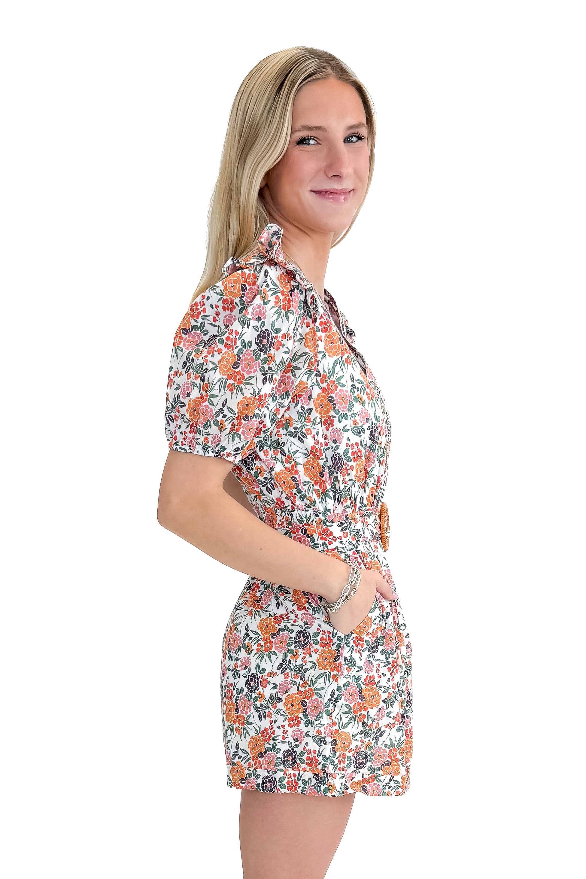 Side view of woman wearing Orange Floral &amp; Lace Romper With Belt against white studio background.