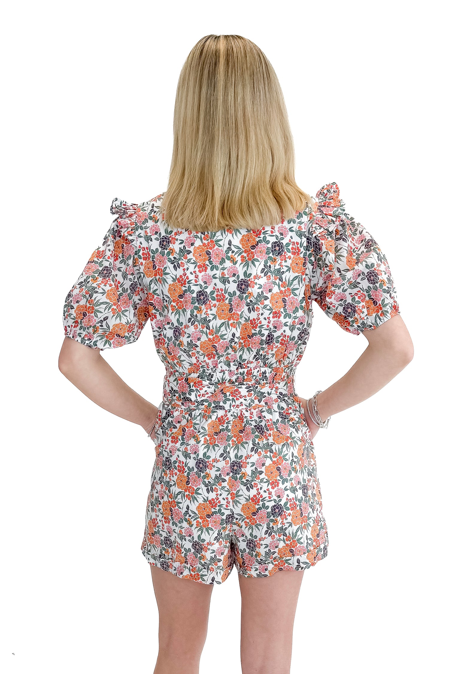 Back view of woman wearing Orange Floral &amp; Lace Romper With Belt against white studio background.