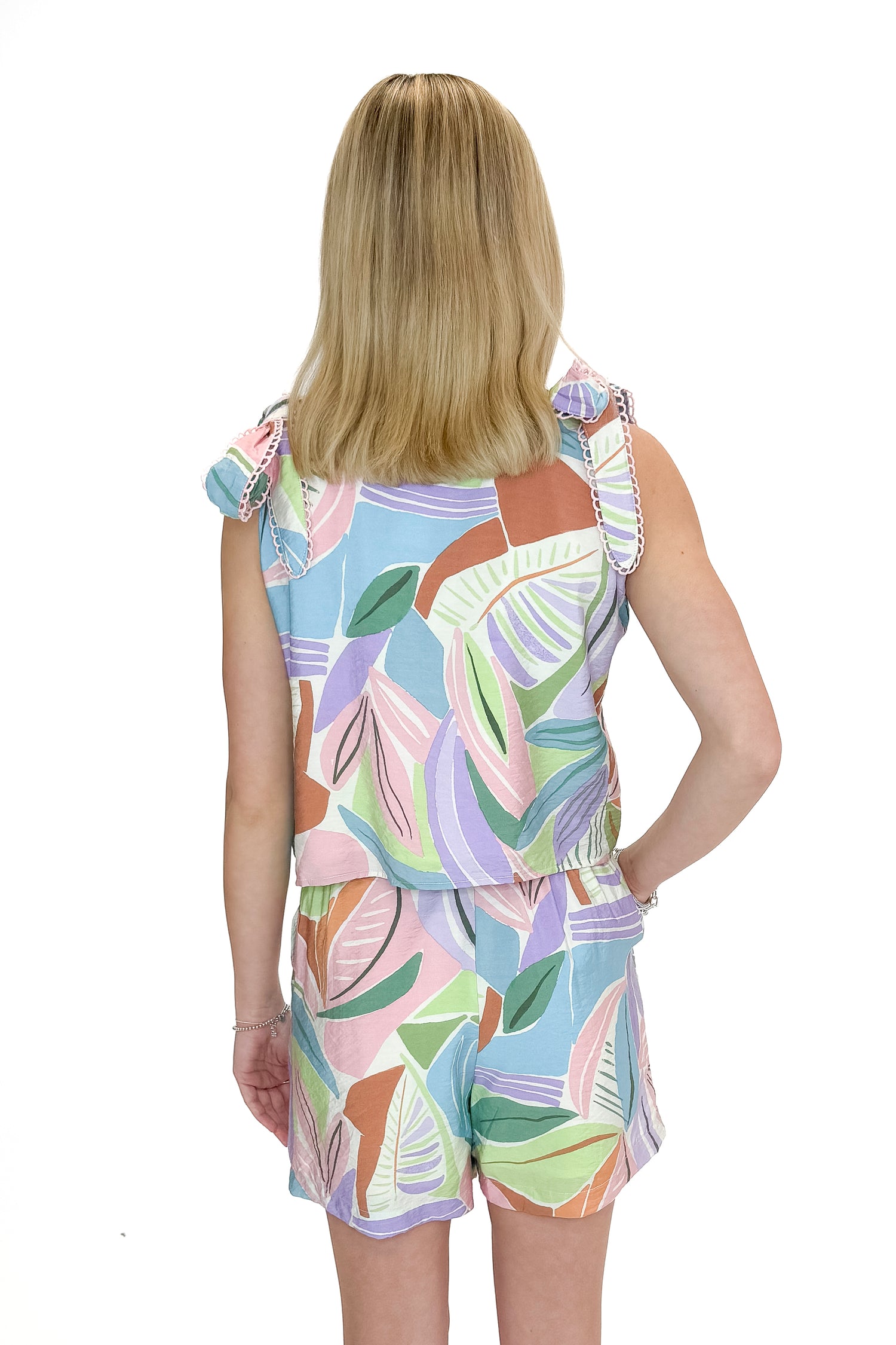Back view of woman wearing Multi Leaf Print tank with matching shorts against white studio background.
