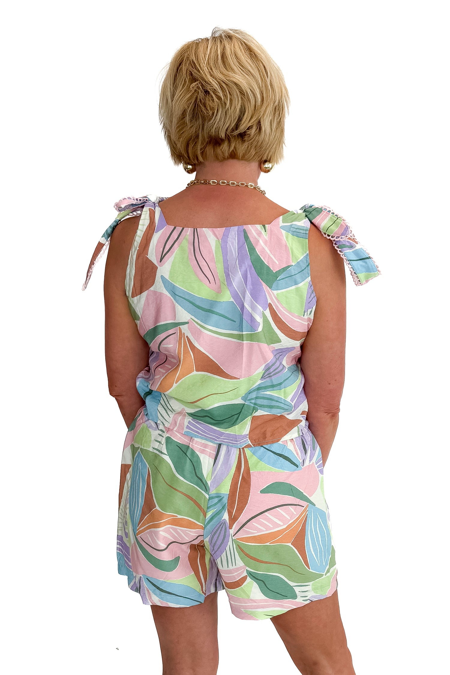 Back view of woman wearing Multi Leaf Print tank with matching shorts against white studio background.