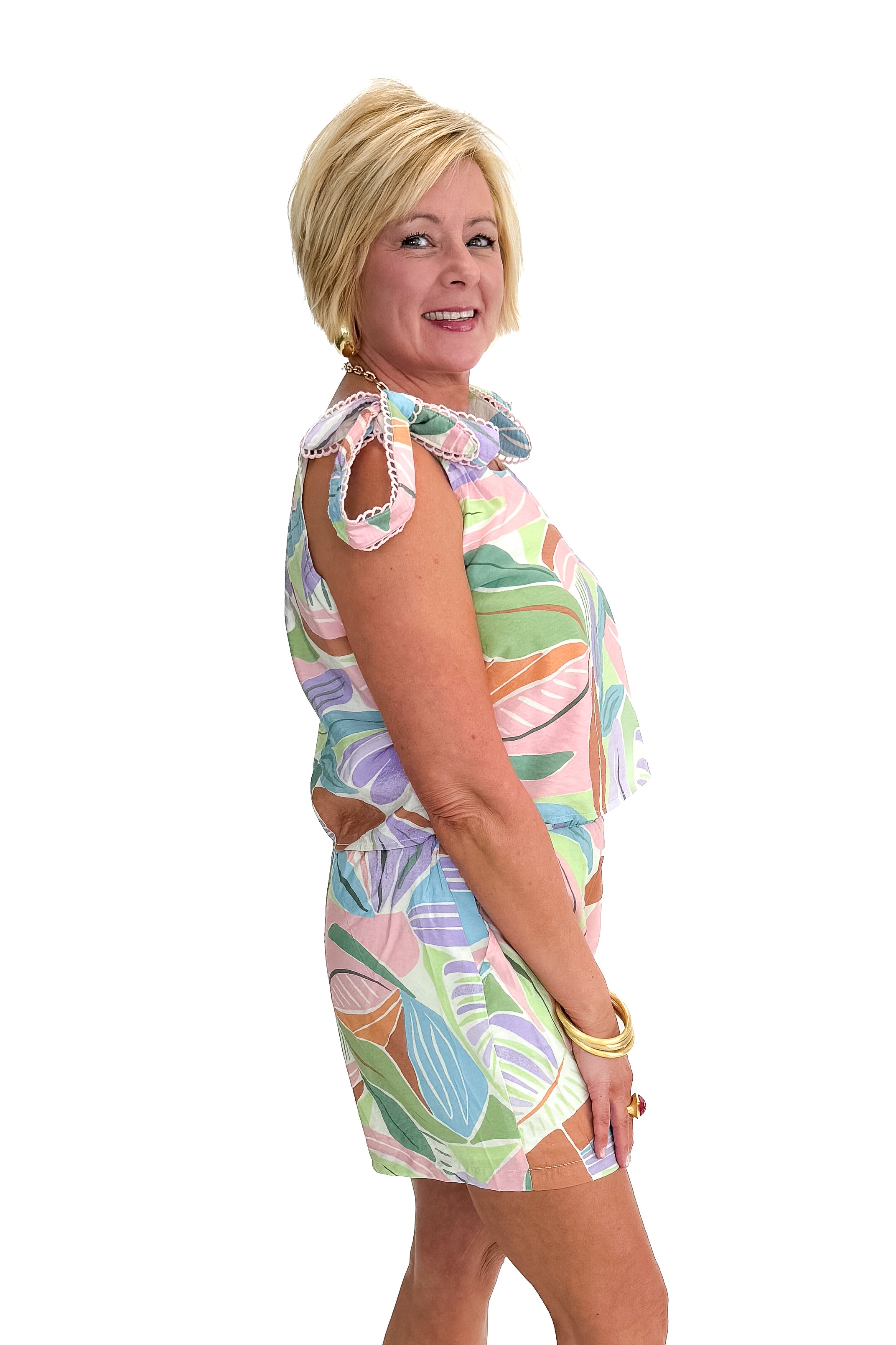 Side view of woman wearing Multi Leaf Print Shorts with matching tank against white studio background.