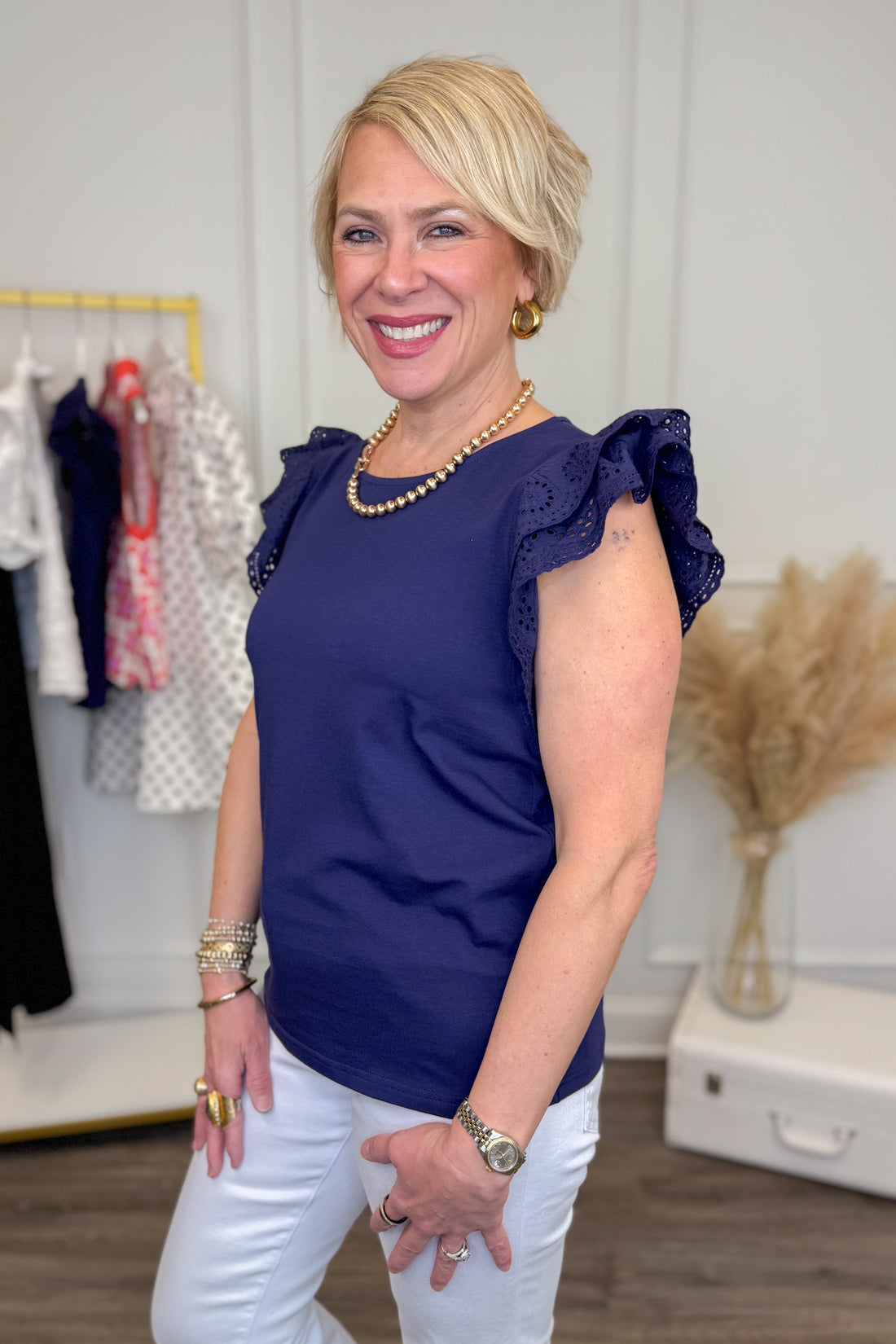 Woman wearing a blue top and white pants in a clothing store.