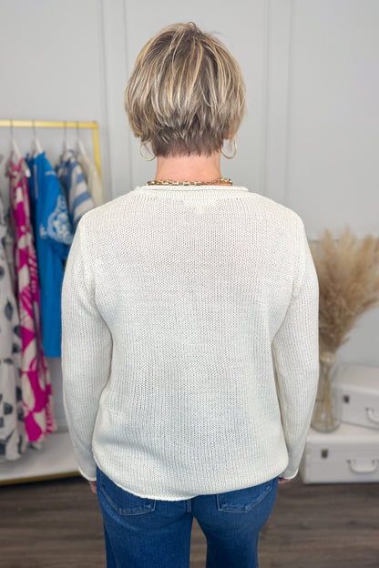 Person wearing a white sweater in a room with clothes and decor.