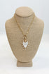 Gold necklace with a heart-shaped pendant on a beige bust against a white background