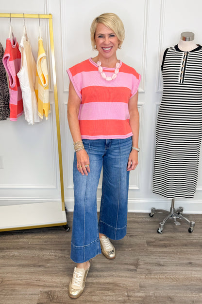 Woman wearing a pink and red striped top with blue jeans in a clothing store.
