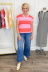Woman wearing a pink and red striped top with blue jeans in a clothing store.