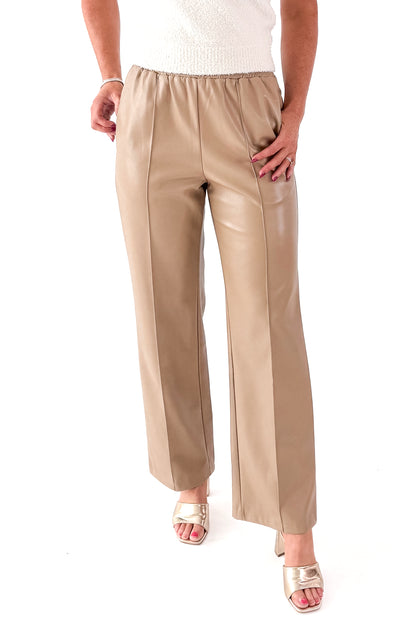 Front view of woman wearing Macchiato Faux Leather Pants and sweater against white studio background.