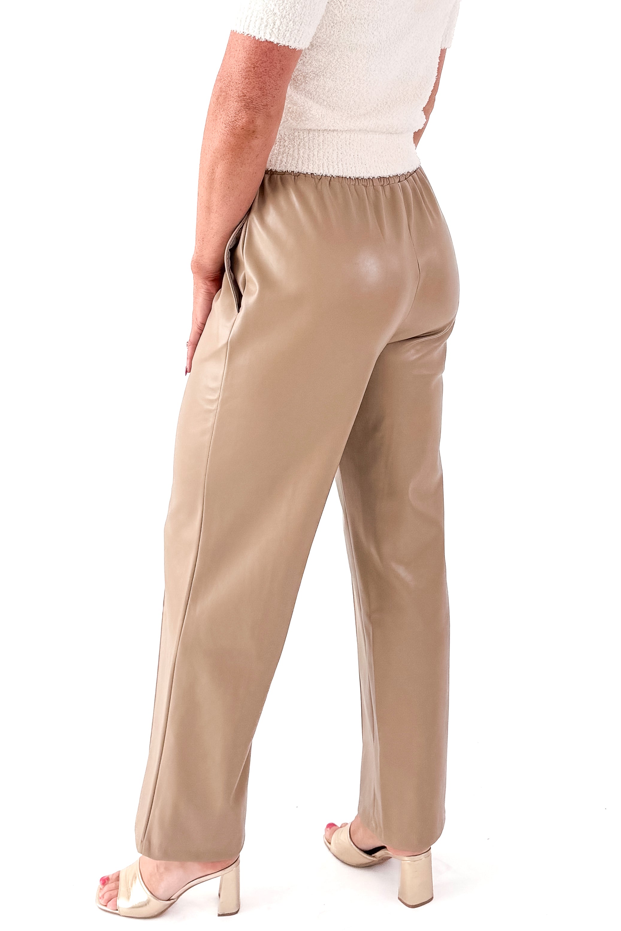 Side view of woman wearing Macchiato Faux Leather Pants and sweater against white studio background.
