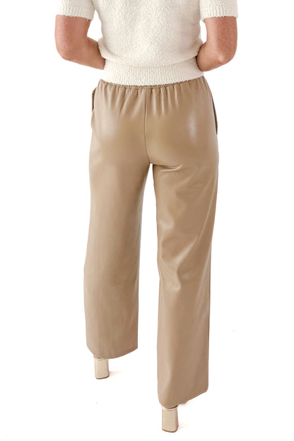 Back view of woman wearing Macchiato Faux Leather Pants and sweater against white studio background.