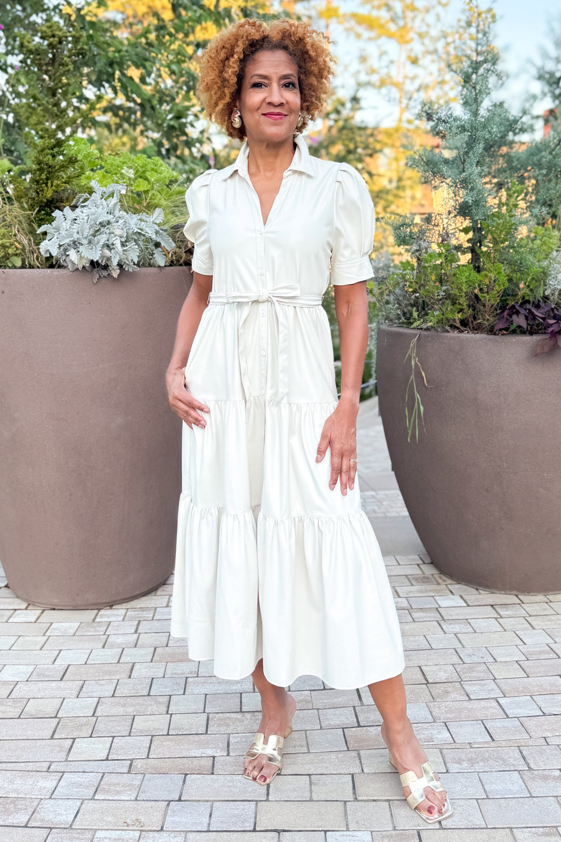 Woman in a white dress standing outdoors with plants in the background