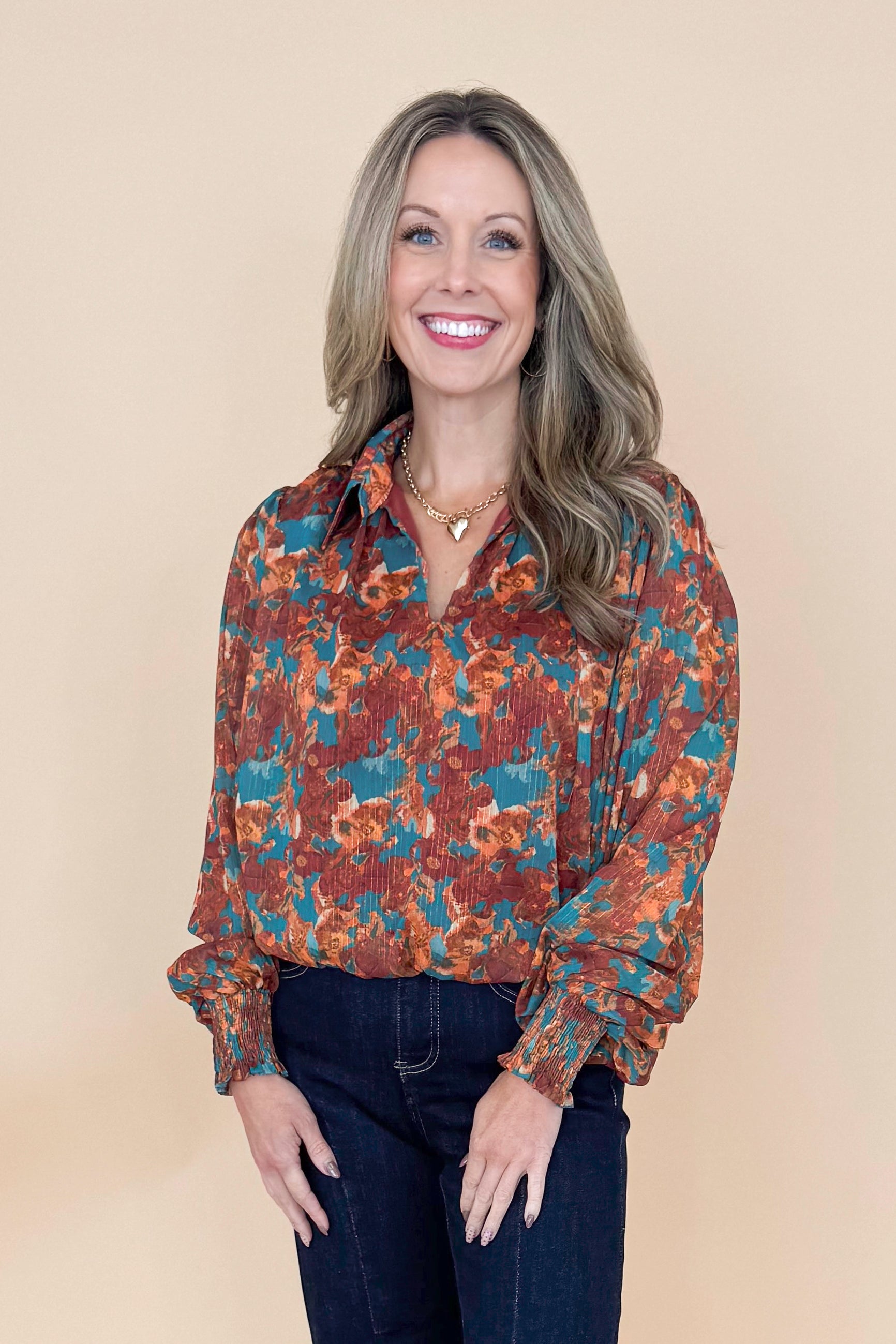 Woman wearing Brown &amp; Teal Printed Top and jeans in a studio with tan background.