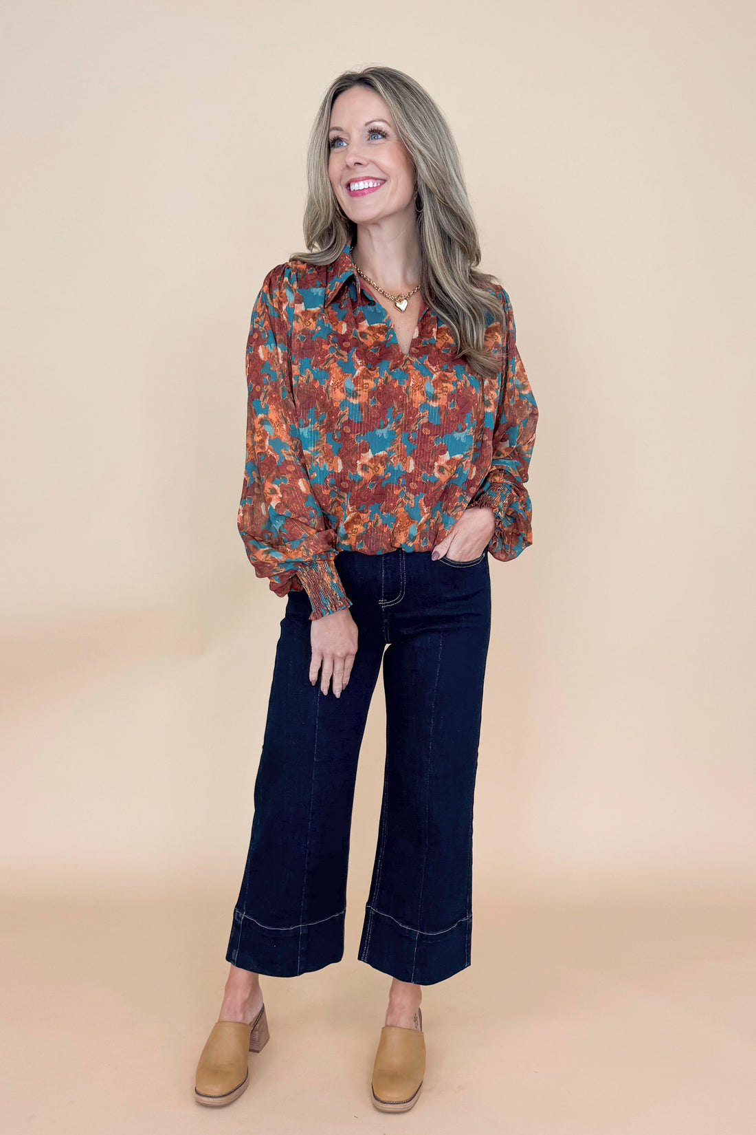 Woman wearing Brown & Teal Printed Top and jeans in a studio with tan background.