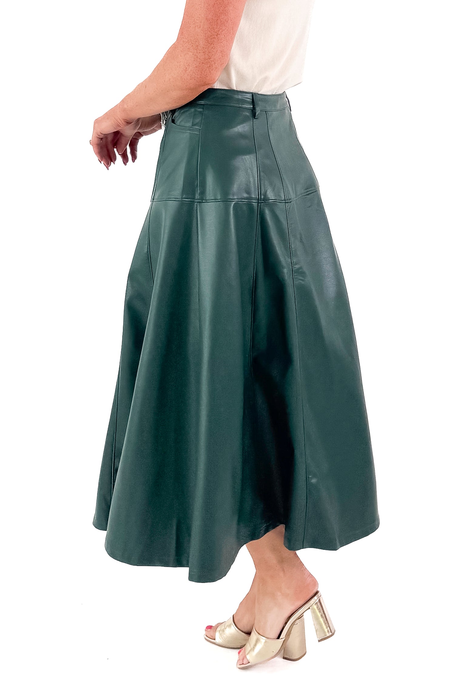 Side view of woman wearing Hunter Green Faux Leather Midi Skirt with top against white studio background.