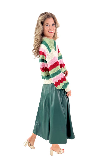 Side view of woman wearing Hunter Green Faux Leather Midi Skirt with top against white studio background.