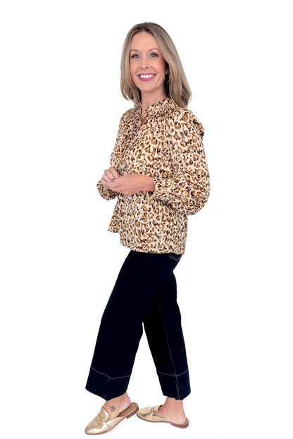 Side view of woman in a studio wearing Taupe Leopard Long Sleeve Top by Fate and jeans against a white background. 