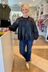 Woman in a black top and blue jeans standing in a store.